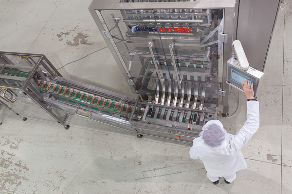 Employee in sterile environment operates equipment for stick pack packaging 
